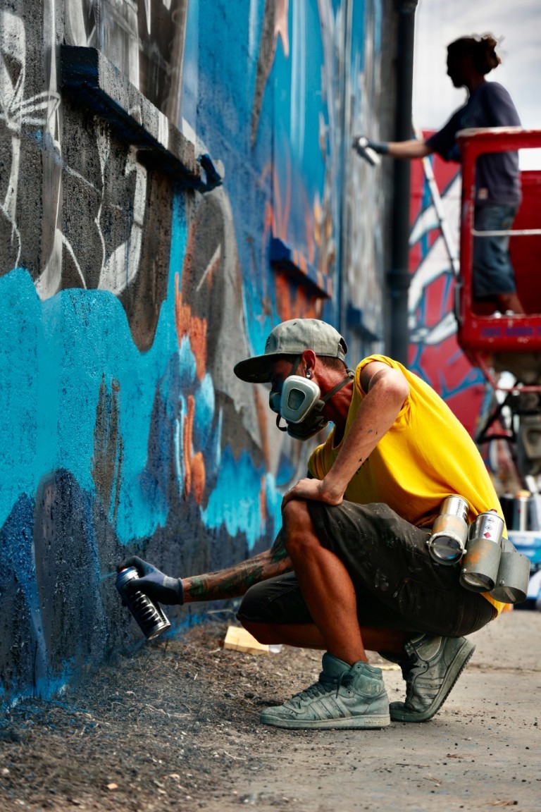 Hista peignant à l'aérosol sur une fresque murale
