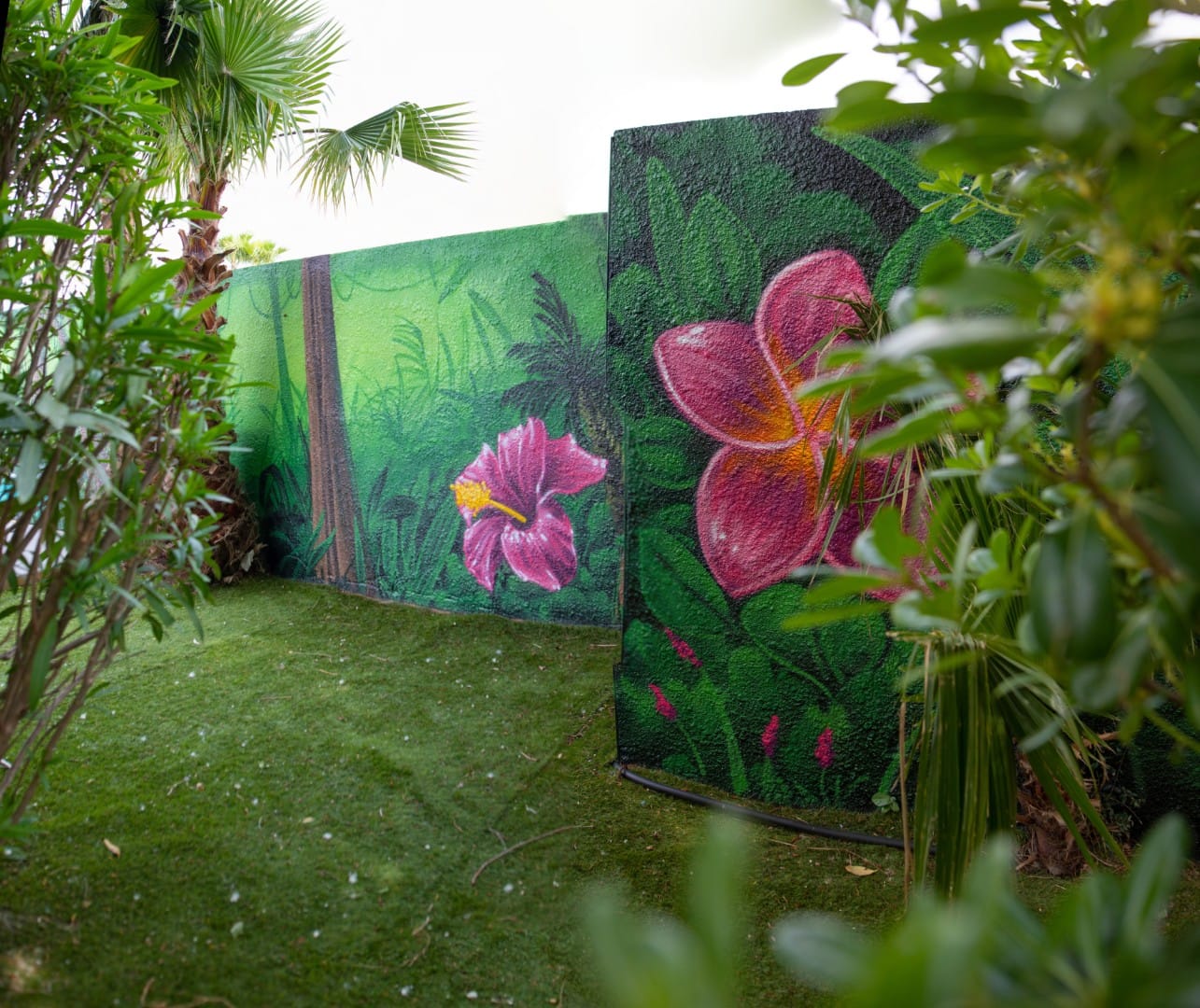 Fleurs géantes peintes par Graffit One au premier plan de la piscine californienne du Camping Les Salisses